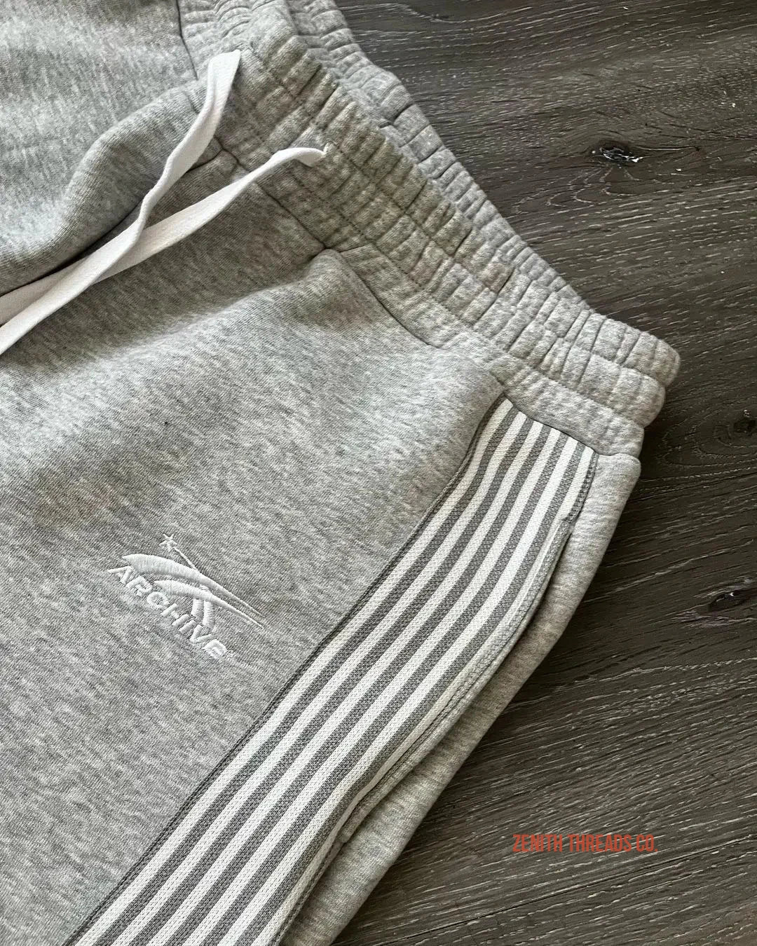 Gray sweatpants with striped side panels and a drawstring waist.