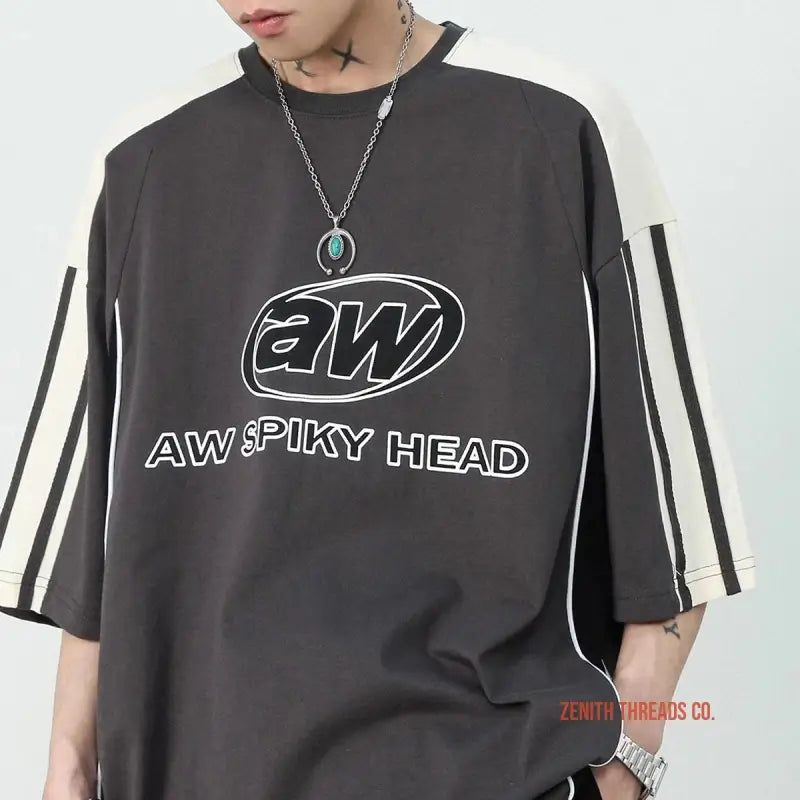 Dark gray t-shirt with ’AW SPIKY HEAD’ text and white striped sleeves.