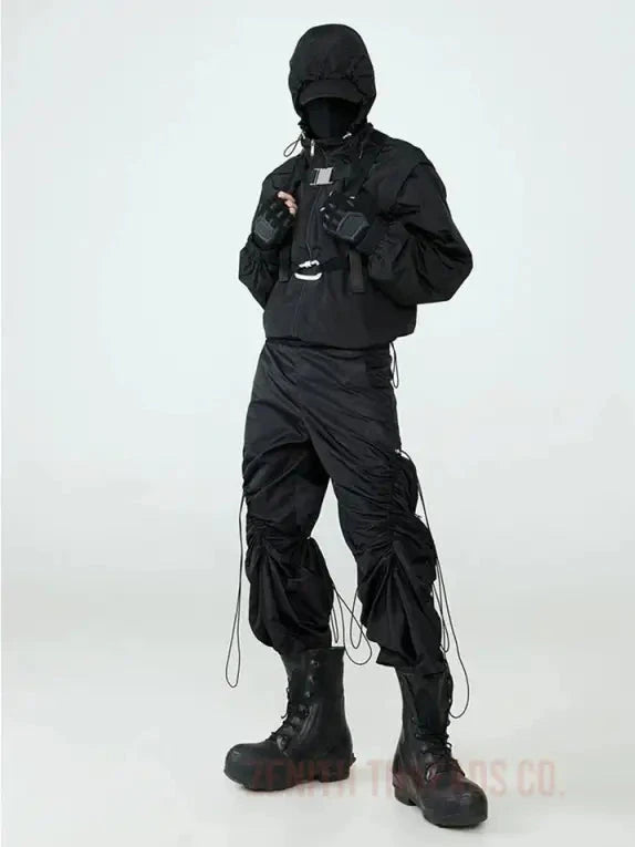 All-black tactical outfit with multiple straps and utility pockets.