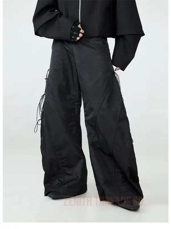 Wide-leg black pants with side drawstring details.