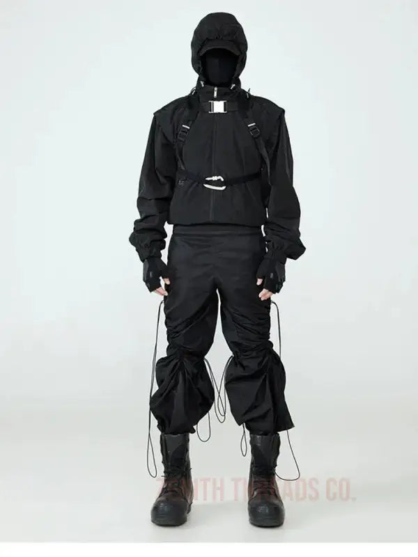 All-black techwear outfit featuring a hooded jacket, cargo pants, and combat boots with multiple straps and utility elements.