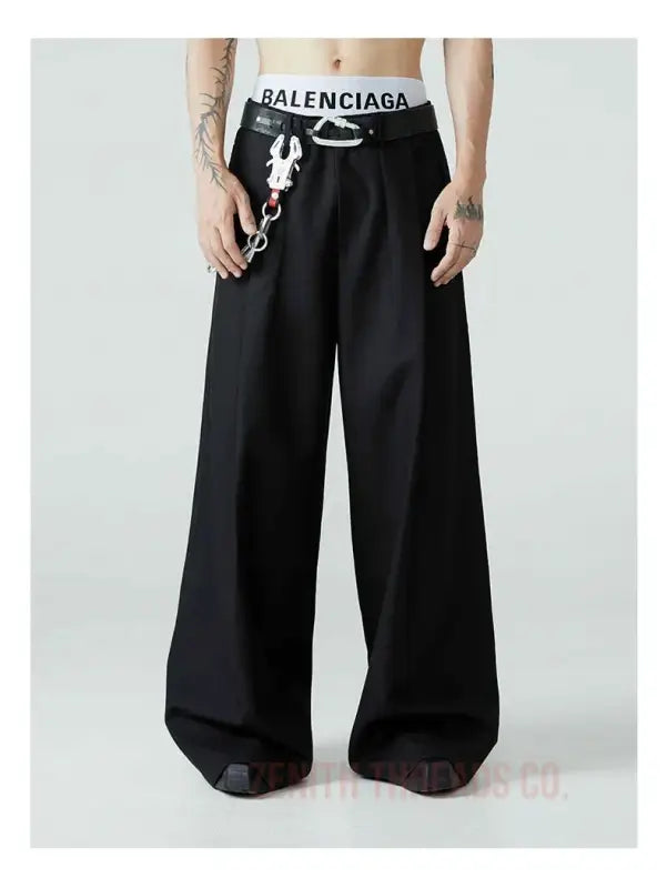 Black wide-leg pants with a Balenciaga logo waistband and chain detail.