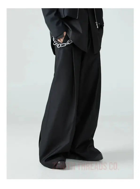 Black wide-leg trousers with decorative embroidery detail at the pocket.