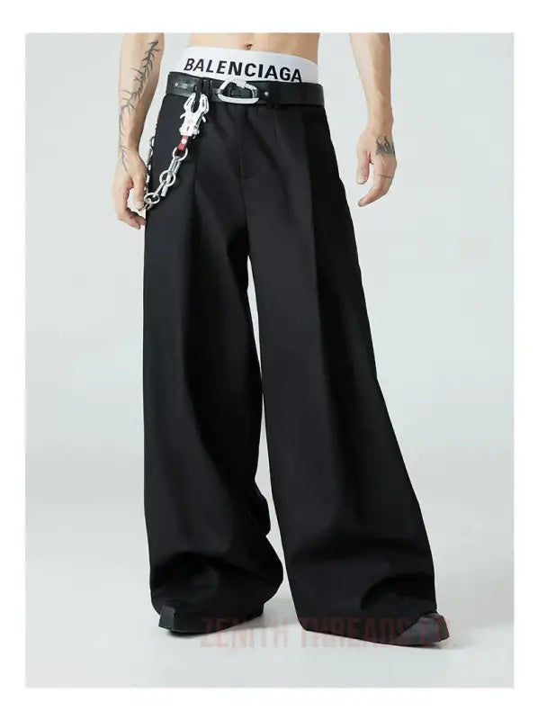 Black wide-leg pants with a Balenciaga waistband and decorative chain detail.