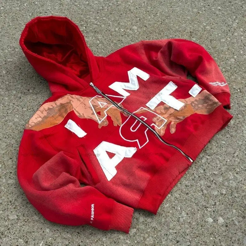 Red hooded sweatshirt with white ’ATM’ lettering lying on ground.