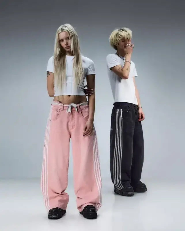 Two people wearing white crop tops and wide-leg track pants with striped details.