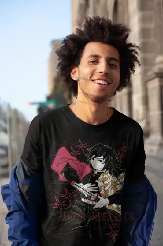 A smiling young person with natural curly hair wearing a graphic t-shirt with blue sleeves.