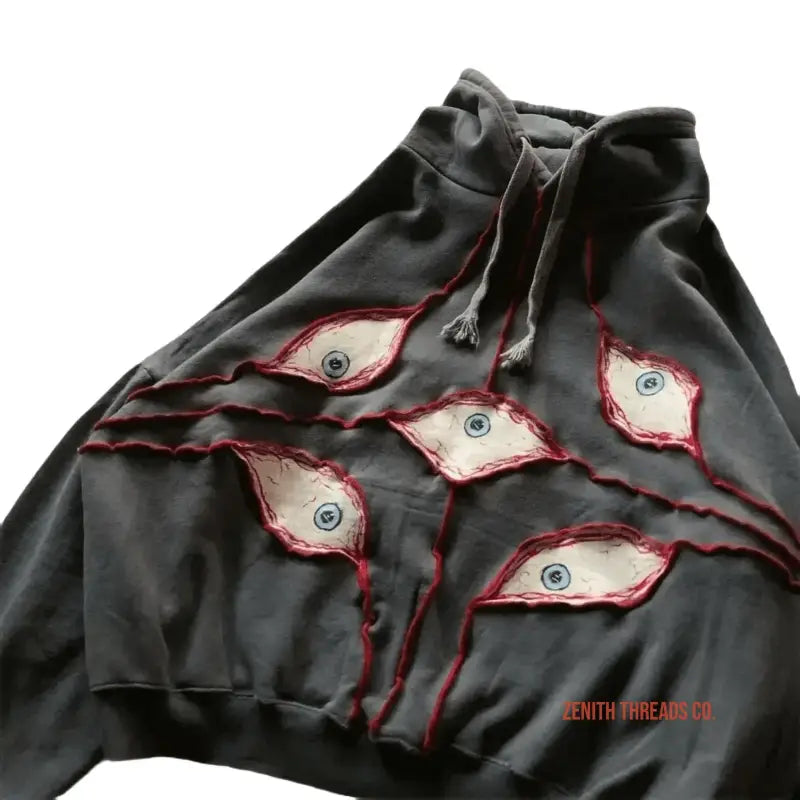 Black hoodie with torn fabric revealing eye designs underneath.