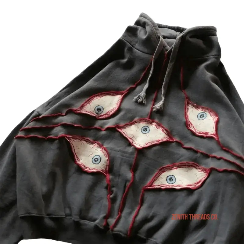 Black hoodie with creepy eye designs torn into the fabric revealing white material underneath with red edging.