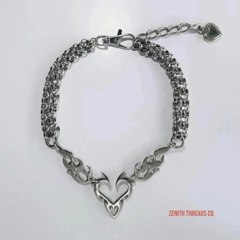 Silver chain bracelet featuring a heart-shaped pendant with flame-like designs.