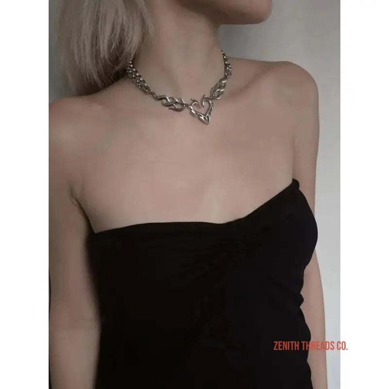 Elegant silver necklace with leaf-like design worn with a black strapless dress.