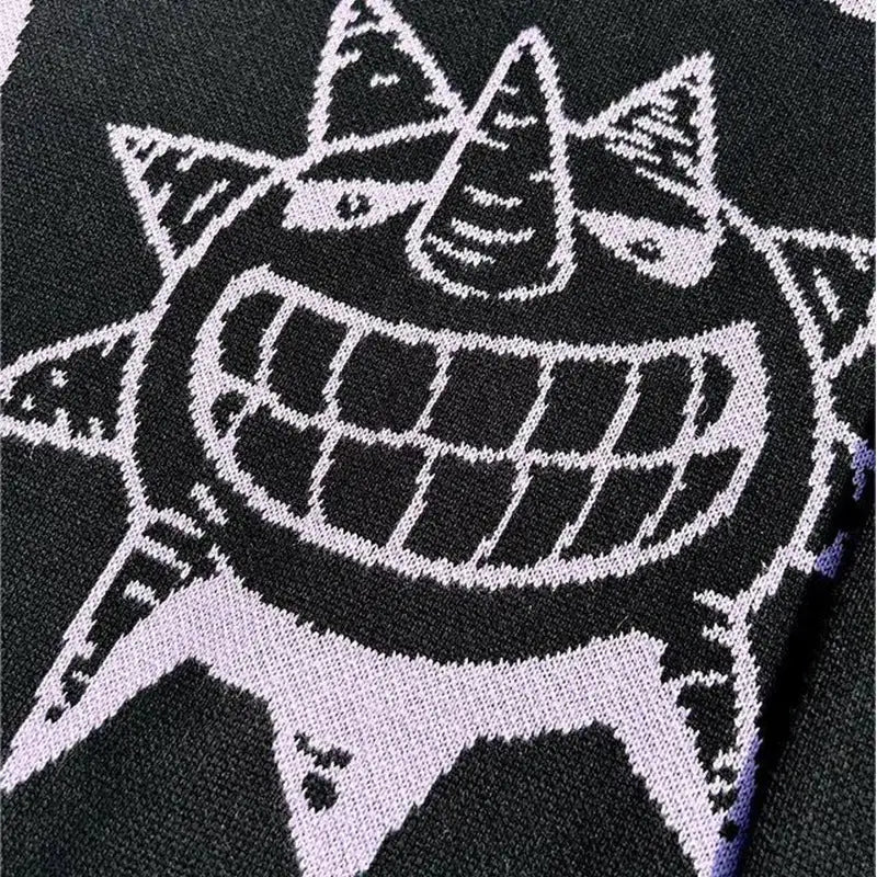 Knitted black and white cartoon character with spiky hair and a big toothy grin.