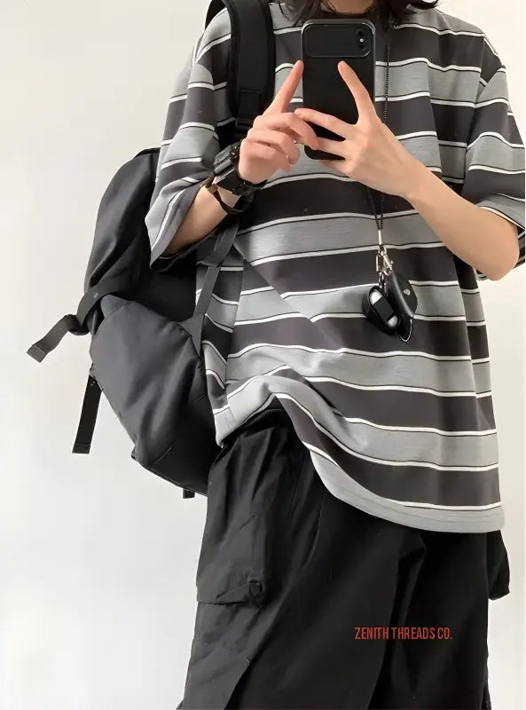 Striped grey and white t-shirt with a backpack and phone.