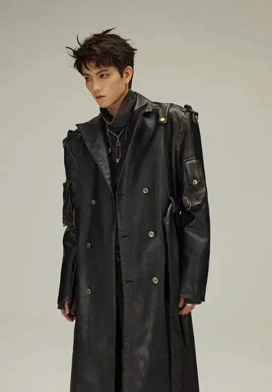 Long black leather trench coat with double-breasted buttons and utility pockets.