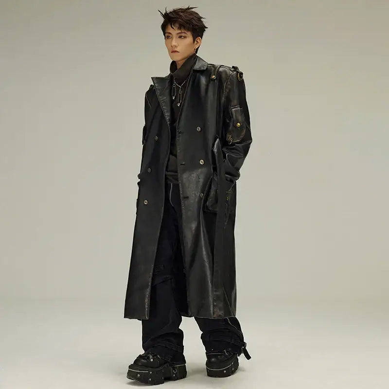 Long black leather trench coat worn with dark casual attire and chunky boots.