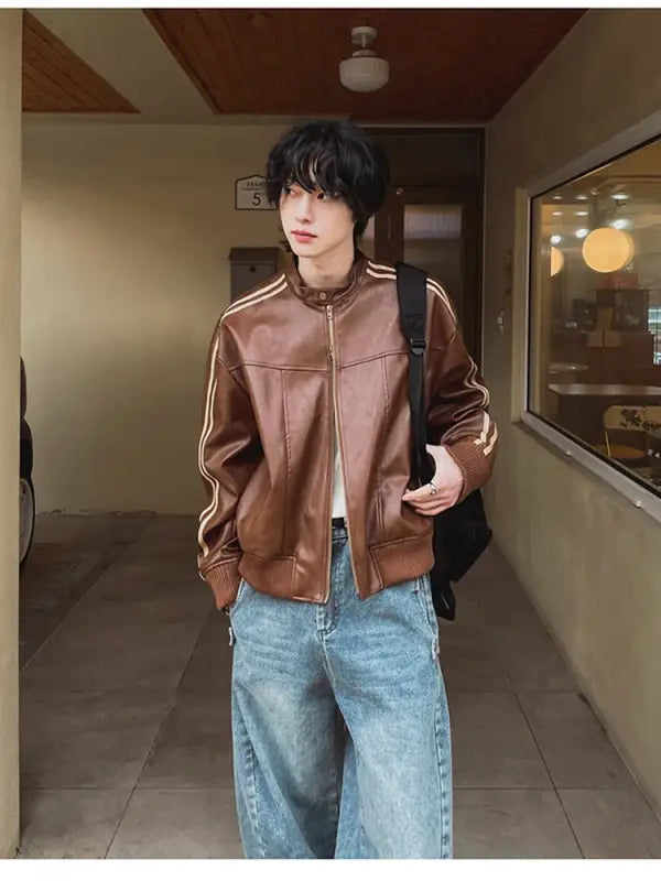 Brown leather bomber jacket paired with light-wash denim jeans.