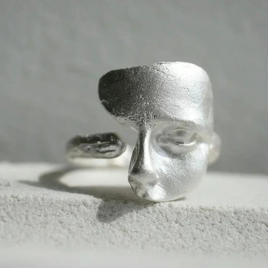 Silver face ring showcasing a masked faces design with an adjustable open-band and metal finish