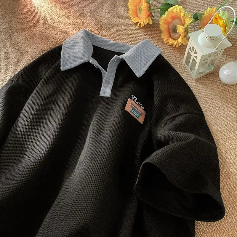 Black polo shirt with gray collar and a small pin attached.