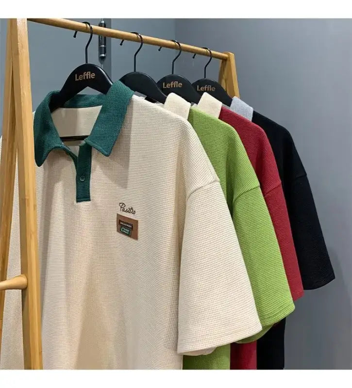 Collection of polo shirts in different colors hanging on a clothing rack.