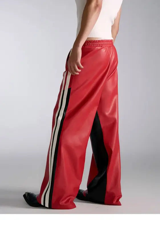 Red athletic track pants with white and black side stripes.