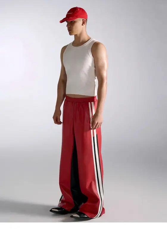 Athletic figure wearing a white tank top, red baseball cap, and red track pants with white stripes.