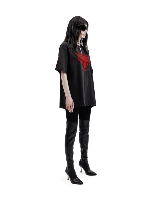 Woman wearing oversized Satan Club graphic tee with thigh-high boots for bold fashion