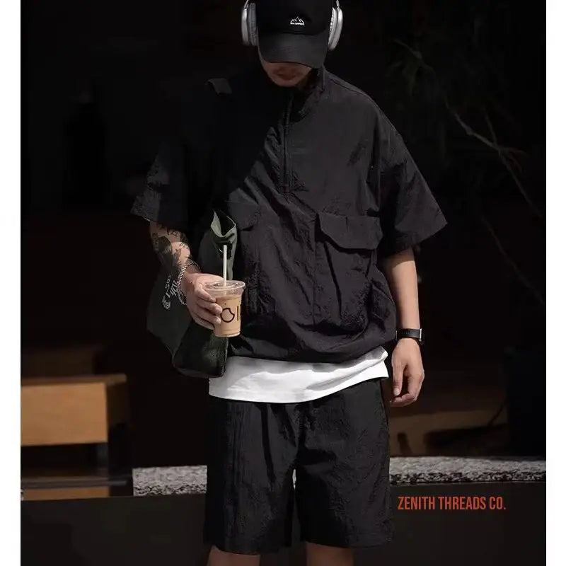 Person wearing black oversized streetwear with white undershirt and headphones.