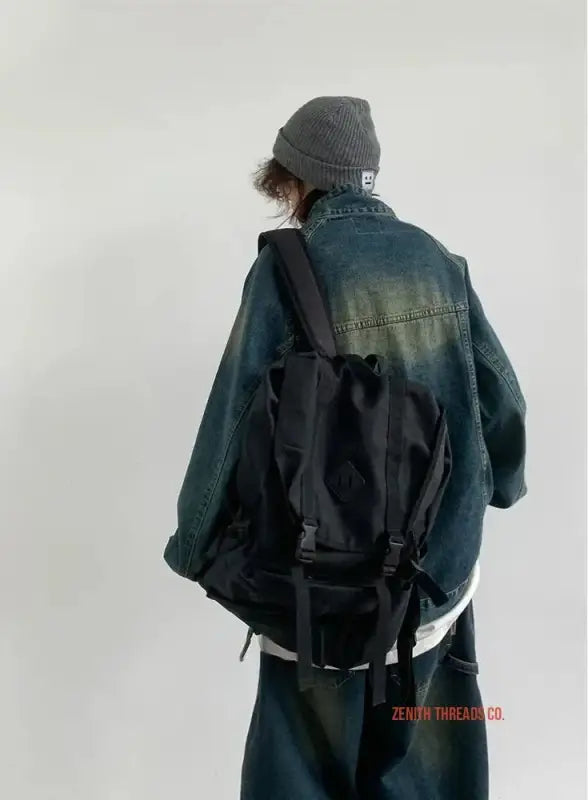 Black backpack worn over a dark denim jacket.