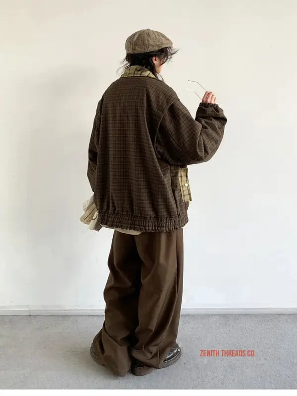 Person wearing an oversized brown sweater, baggy pants, and a newsboy cap.