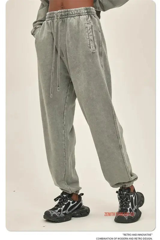 Sage green jogger-style sweatpants with drawstring waist and elastic cuffs worn with black chunky sneakers.