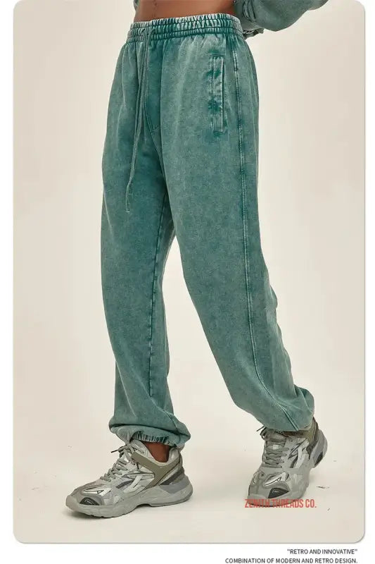 Mint green acid-washed sweatpants paired with gray athletic sneakers.