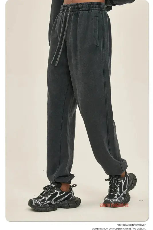 Dark gray jogger-style sweatpants with elastic cuffs worn with black athletic sneakers.