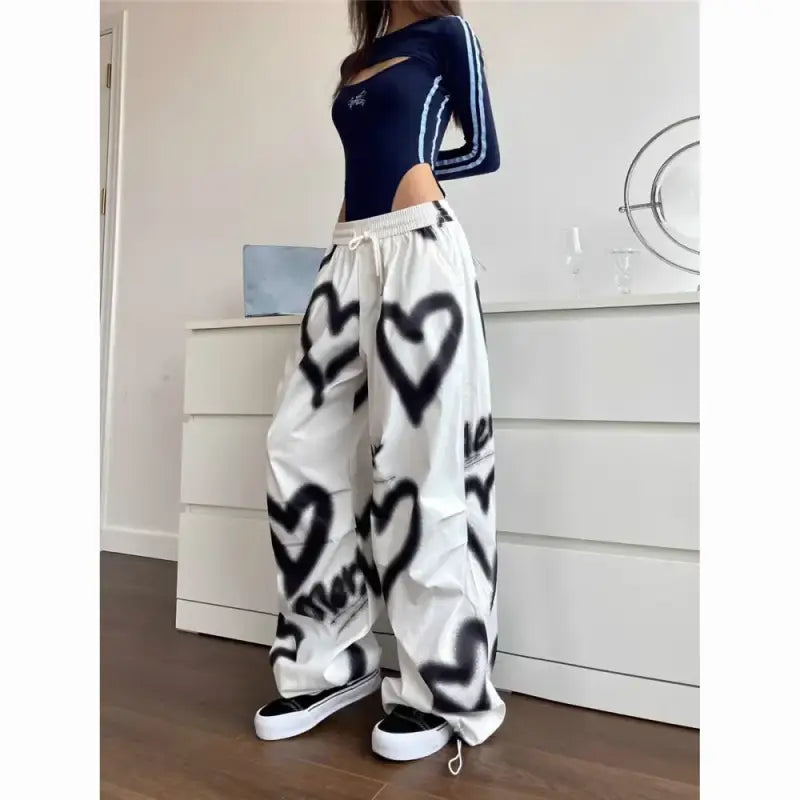 White baggy sweatpants decorated with black spray-painted heart designs.