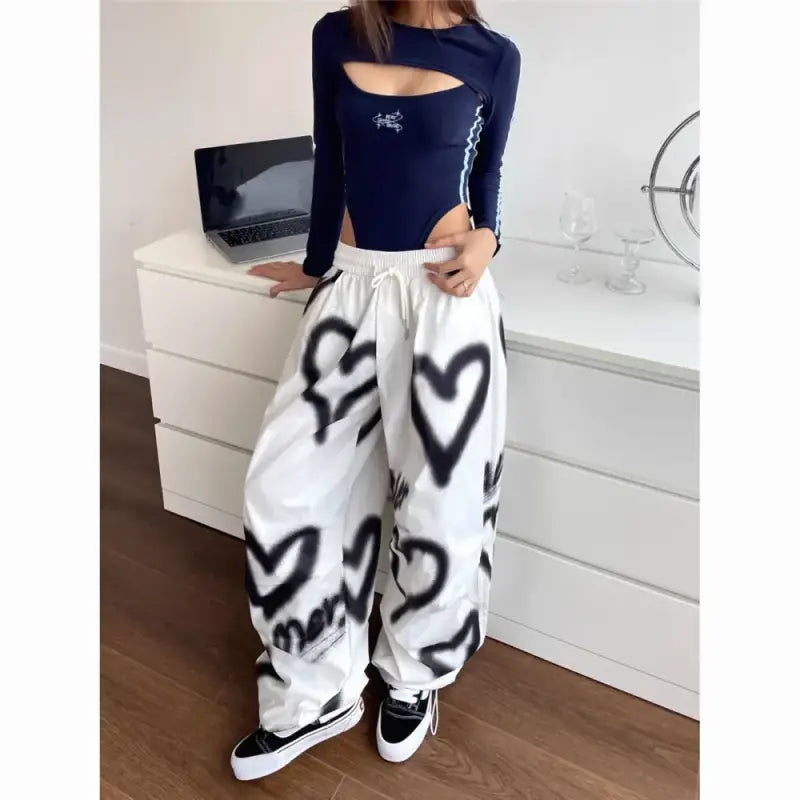 White baggy sweatpants with black spray-painted heart designs paired with a navy blue cutout top.