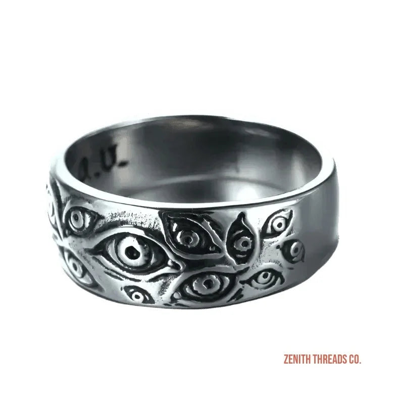 Silver ring with multiple embossed eye designs carved into its surface.